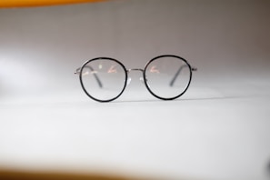 A pair of modern, lightweight reading glasses with thin metal frames on a marble surface