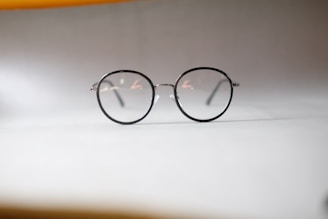 A pair of modern, lightweight reading glasses with thin metal frames on a marble surface