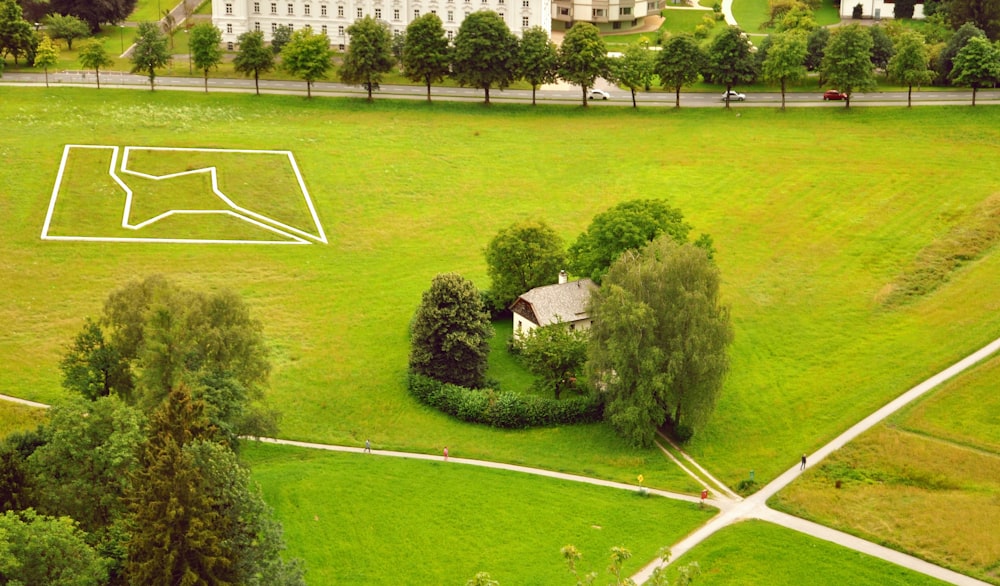 a large green field with trees and a building in the background