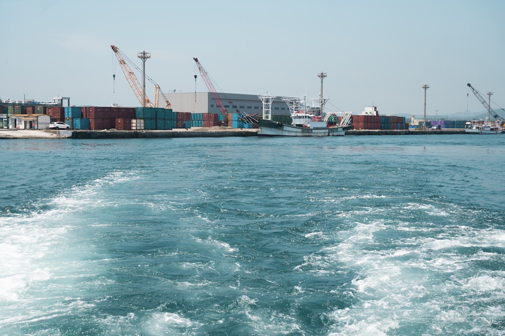 a body of water with a boat in it and cranes in the background