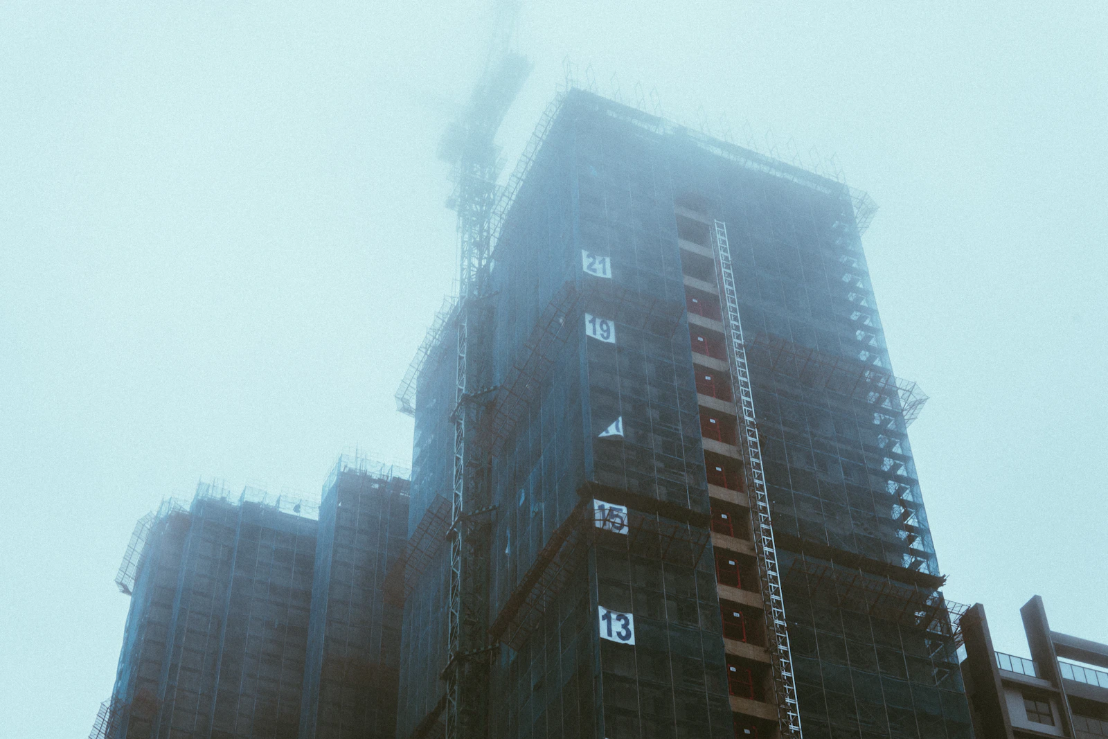 Prédio alto em construção visto de baixo durante obra de incorporação imobiliária