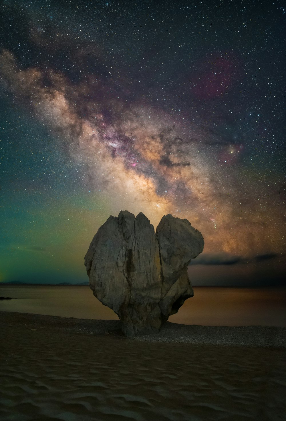 a rock formation in the middle of a desert with stars in the sky