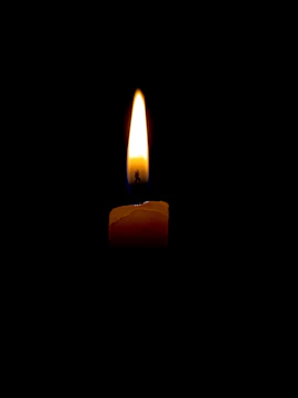 A softly lit candle flame flickering against a desert gold background symbolizing hope.
