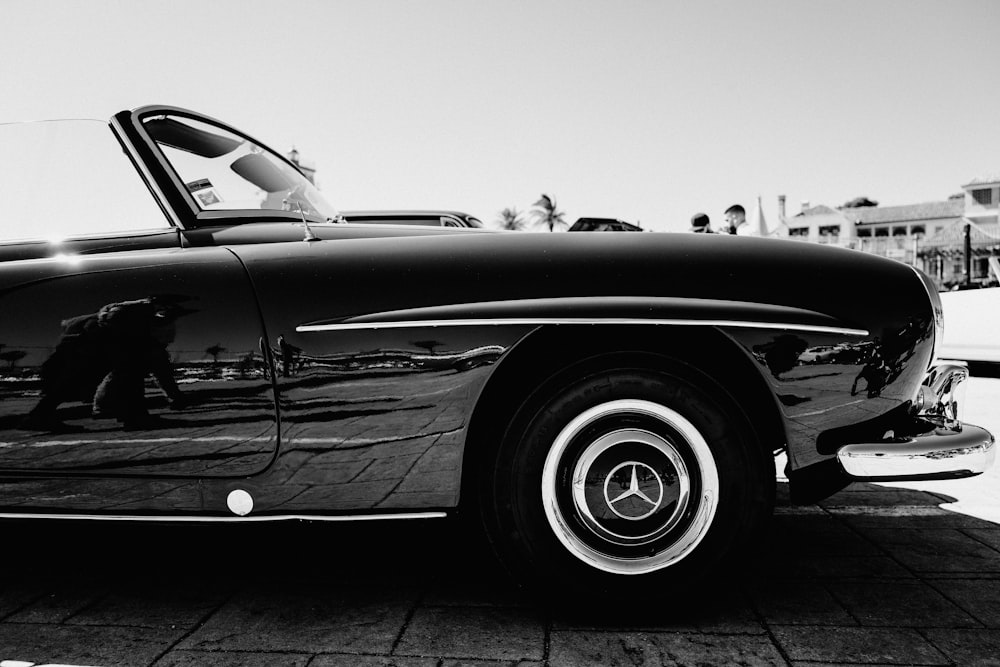 a black and white photo of a car parked on a brick road