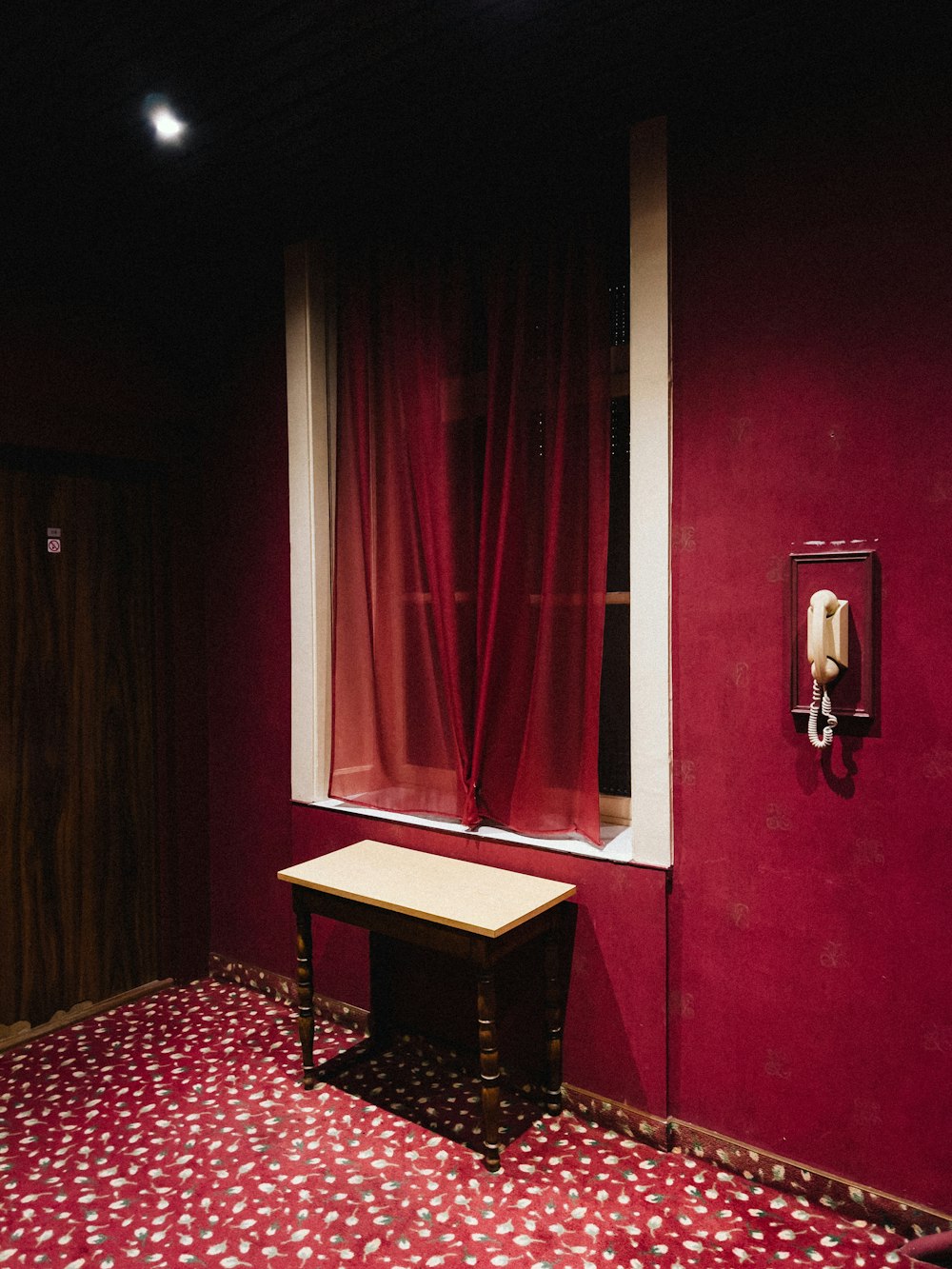 a room with a table and a window with red curtains