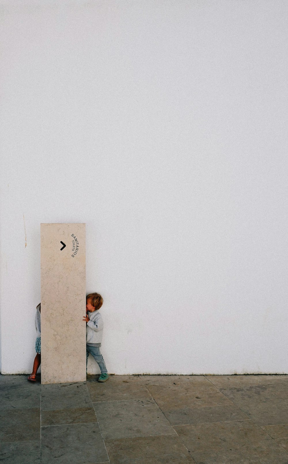 a child standing next to a white wall