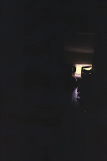 A dimly lit room with a flickering computer screen showing a horror game scene.