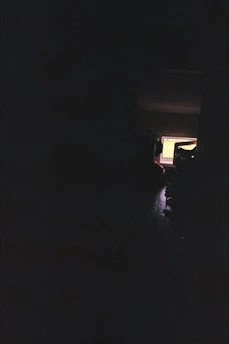 A dimly lit room with a flickering computer screen showing a horror game scene.