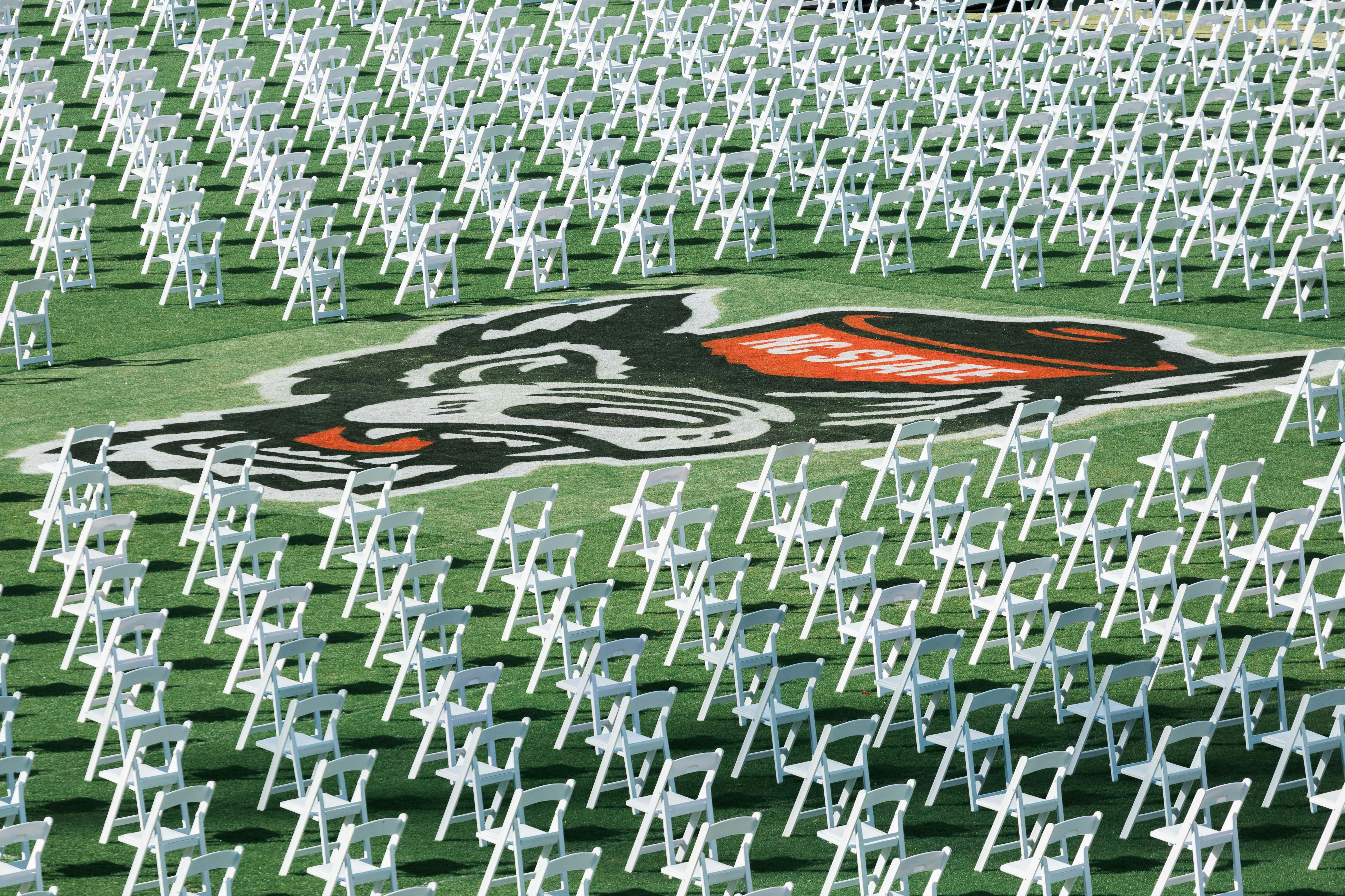 a race car driving through a large group of white chairs