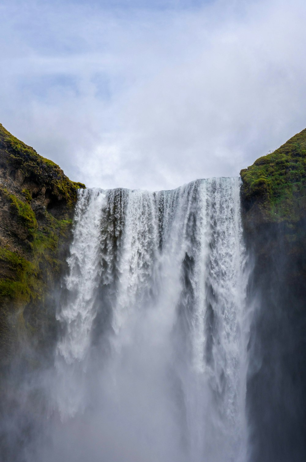 a waterfall with green grass and rocks