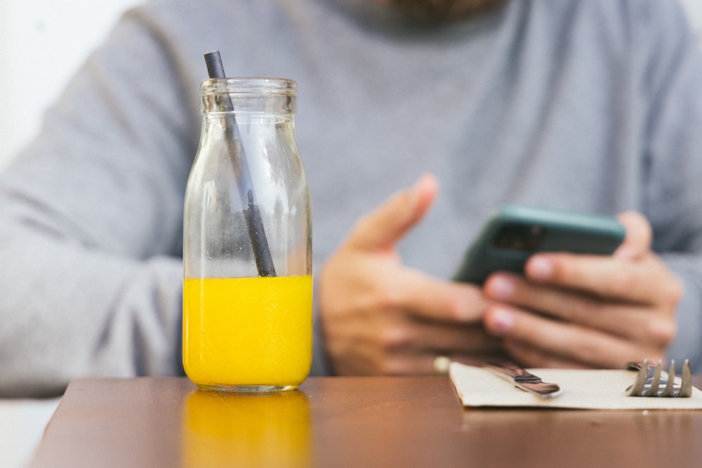 a person holding a phone and a glass of liquid