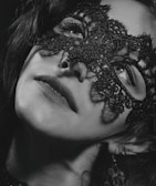 A close-up of a model's expressive eyes behind a delicate lace mask.