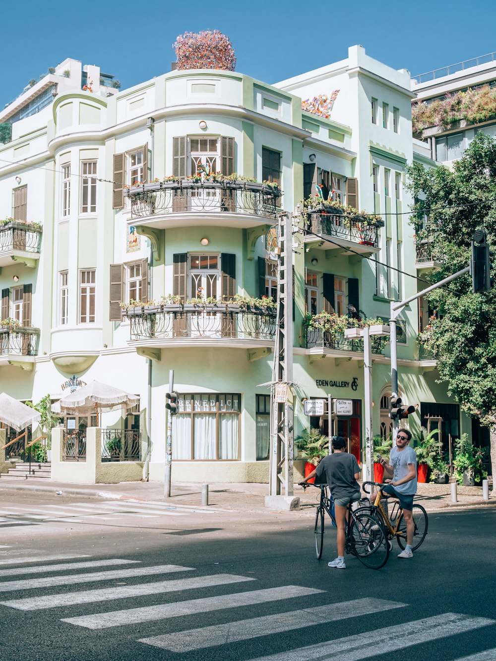 um casal de pessoas andando de bicicleta em frente a um grande edifício branco