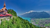 a building on a hill with a lake and mountains in the background