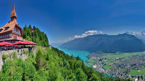 a building on a hill with a lake and mountains in the background
