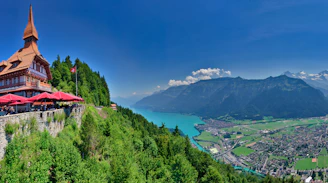 a building on a hill with a lake and mountains in the background