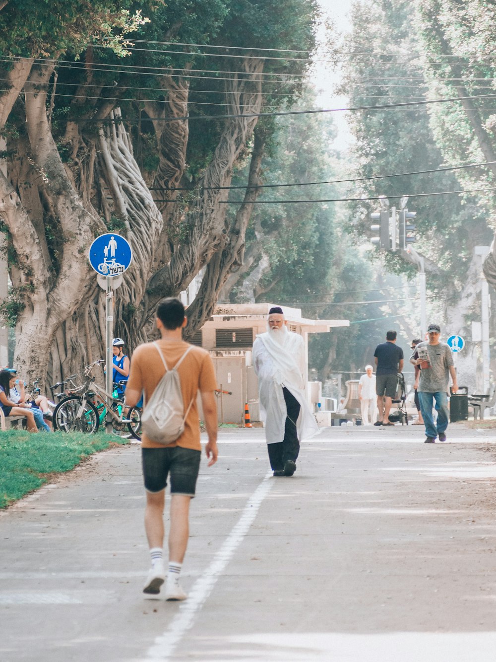 a couple of men walking down a street with trees on either side