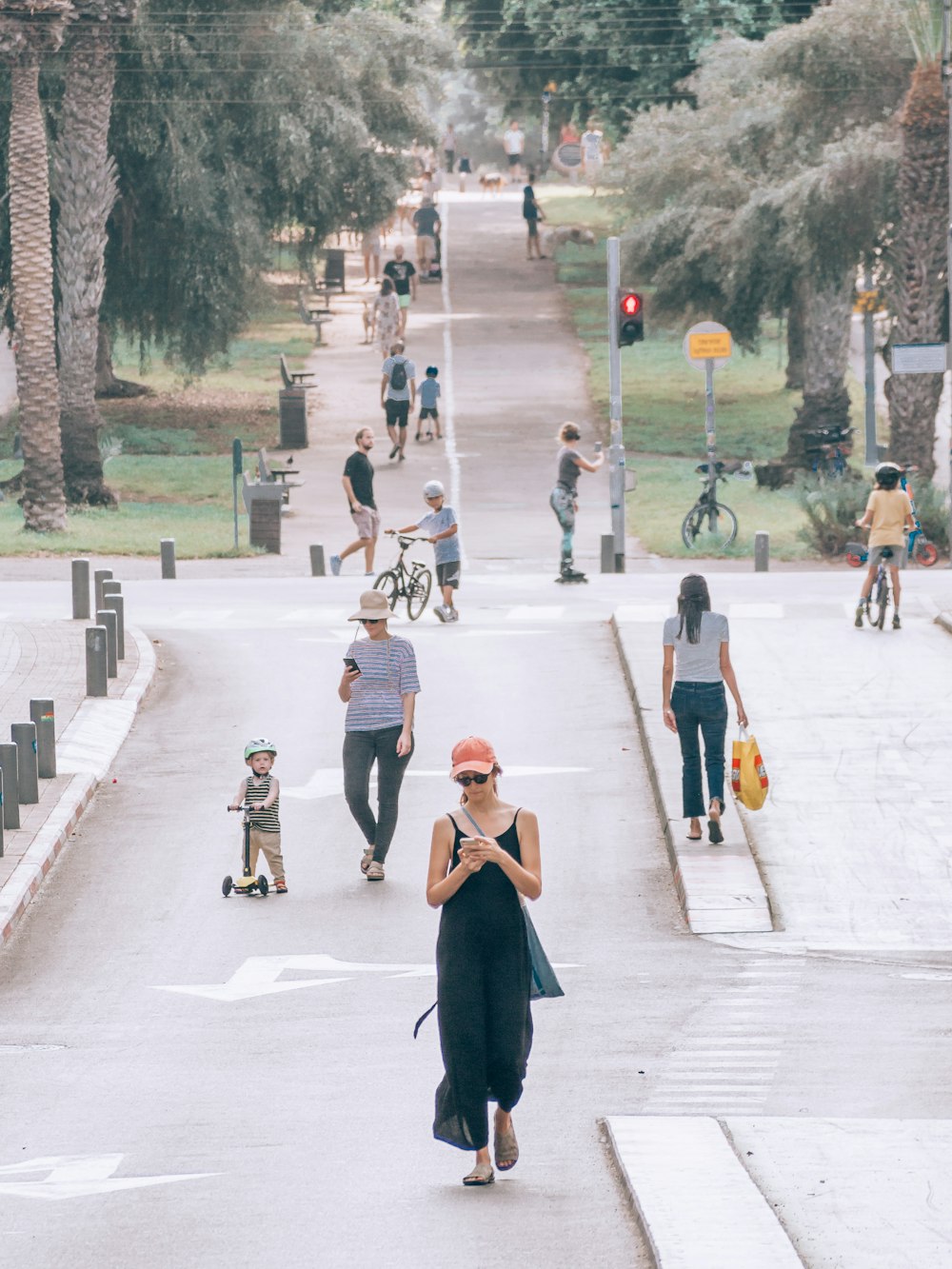 a person in a dress walking down a street with people and trees