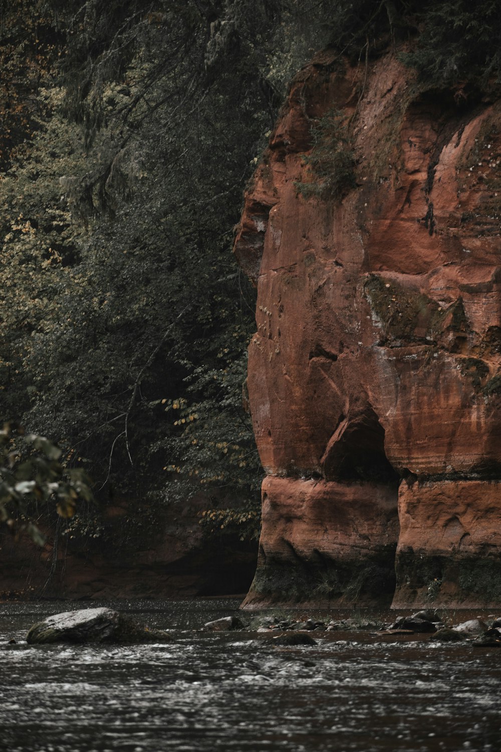 a large rock cliff next to a river