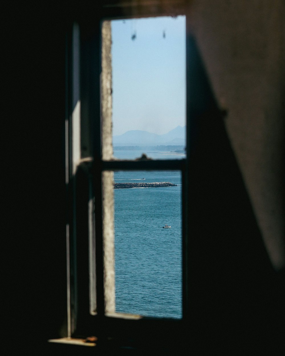 a window with a view of the ocean and mountains