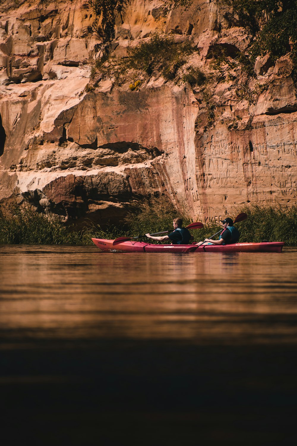 a group of people in a canoe in front of a cliff