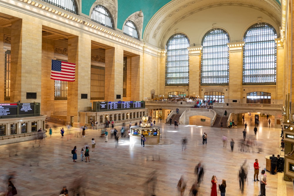 a large room with people and a flag in it with Grand Central Terminal in the background