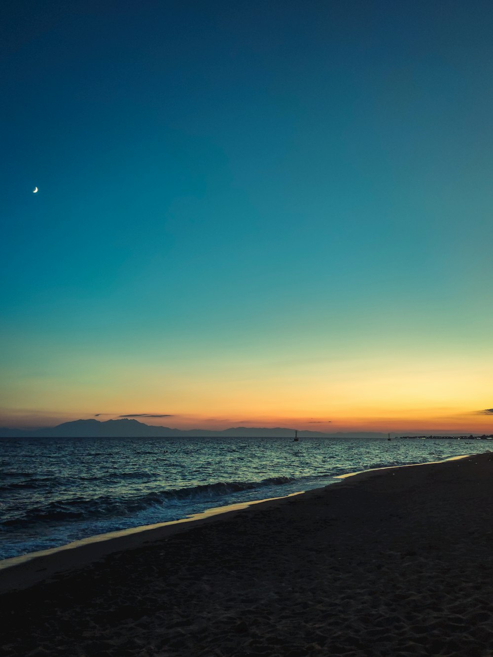 a beach with a body of water and a blue sky