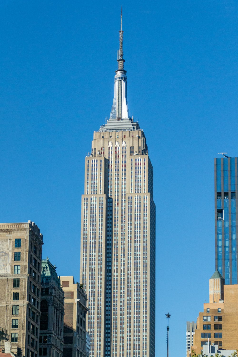a tall building with a pointy top with Empire State Building in the background