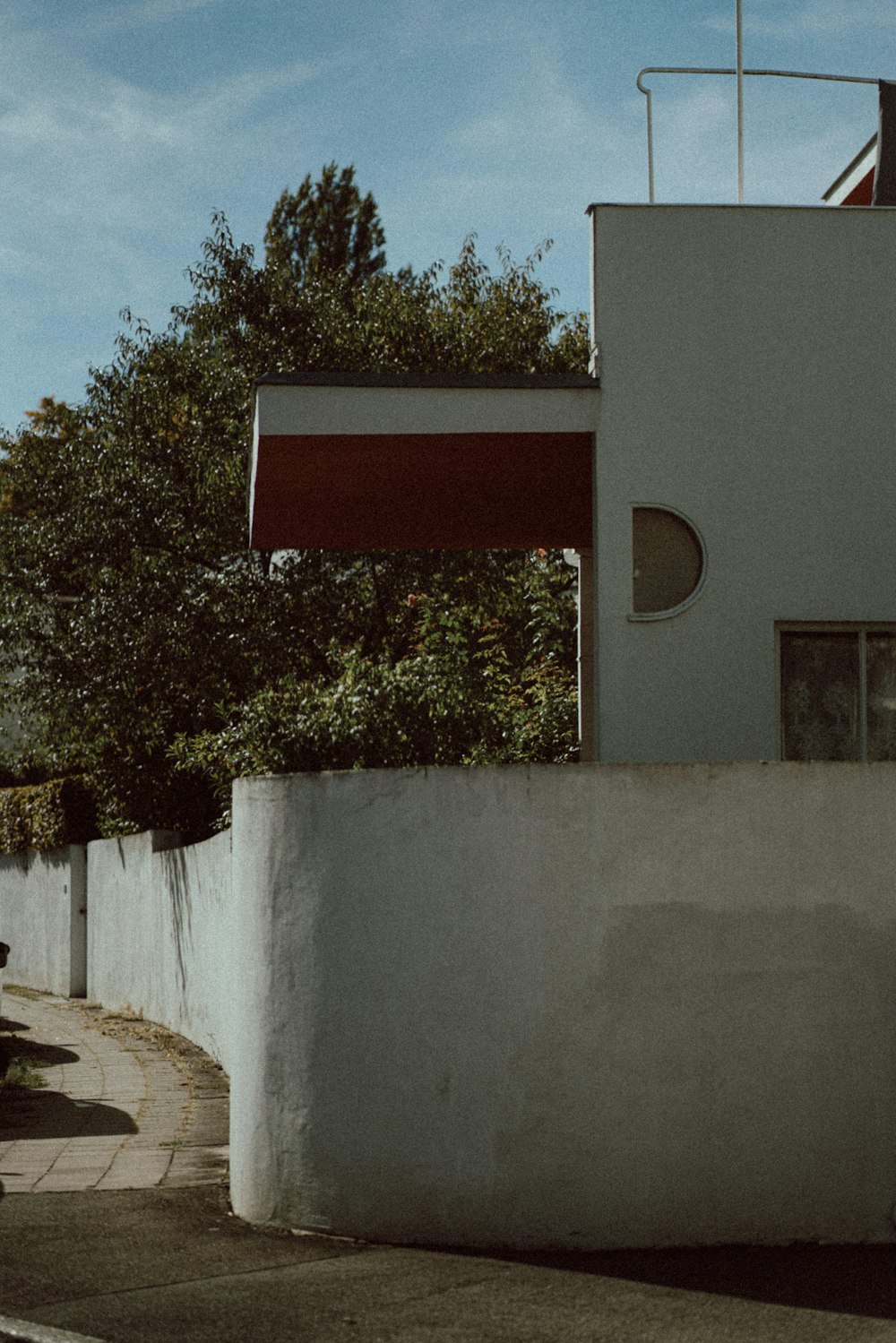 a white wall with a tree and a building in the background