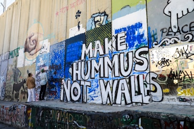 a group of people standing next to a wall covered in graffiti