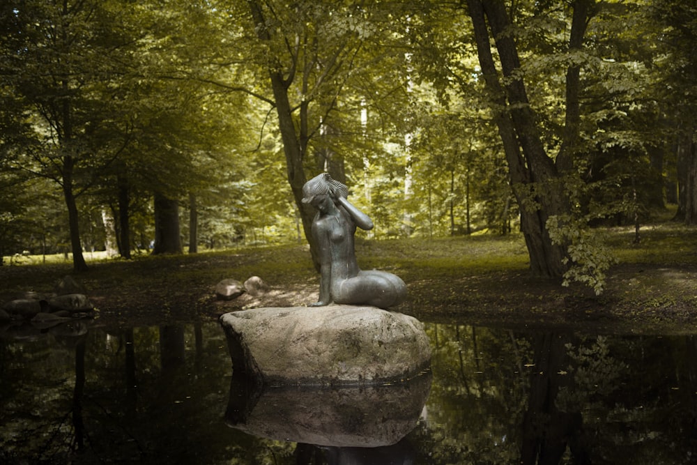 Una estatua de un gato en una roca en un estanque