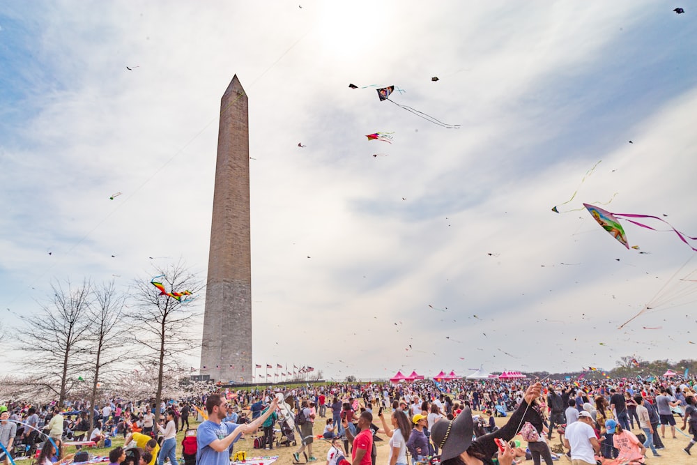 a crowd of people flying kites with Washington Monument in the background