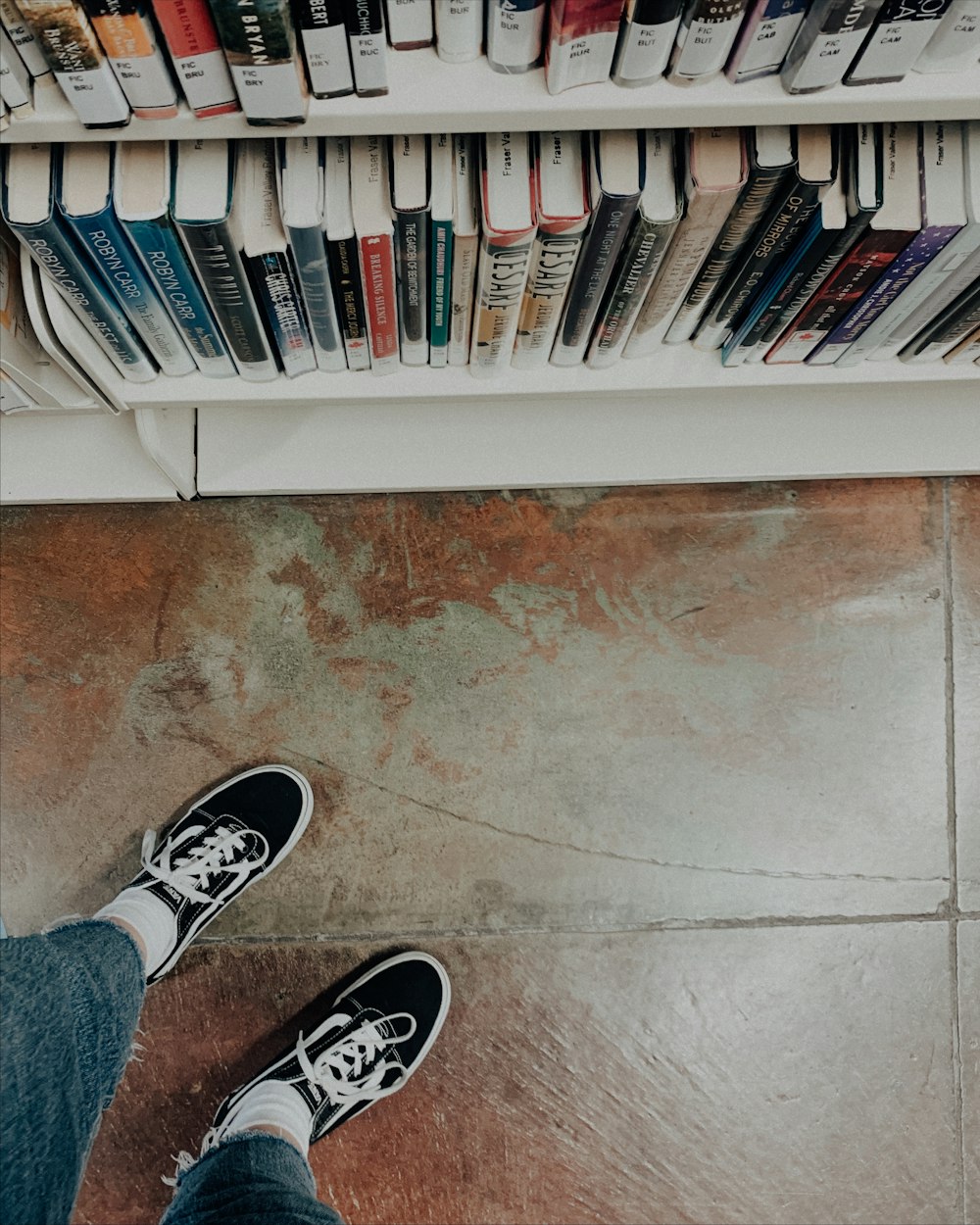 a person's feet on a shelf with books on it