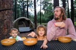 a person and two children sitting at a table with food