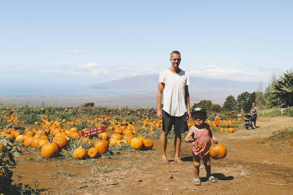 a man and a child standing in front of pumpkins