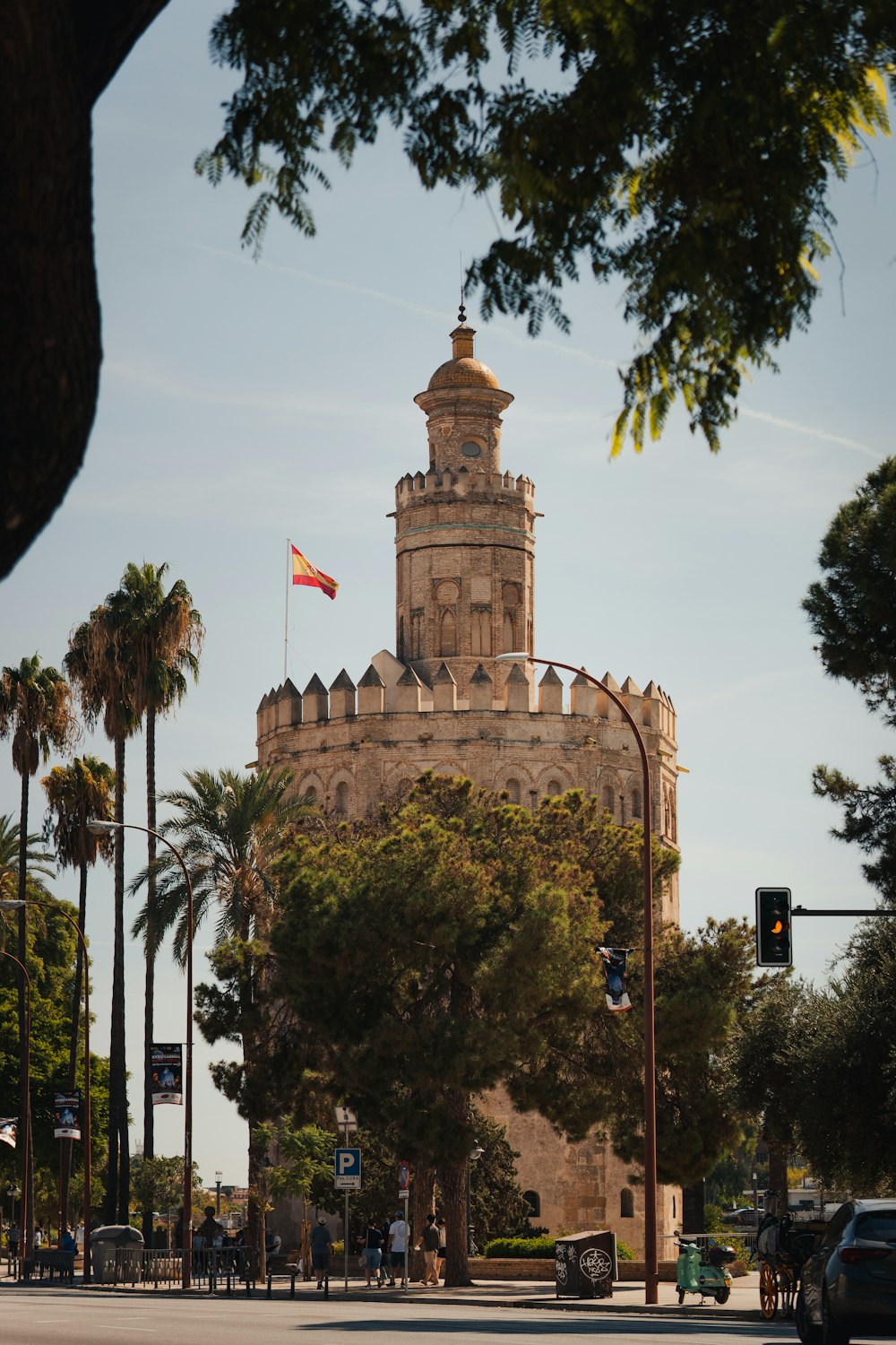 a large building with a flag on top with Torre del Oro in the background