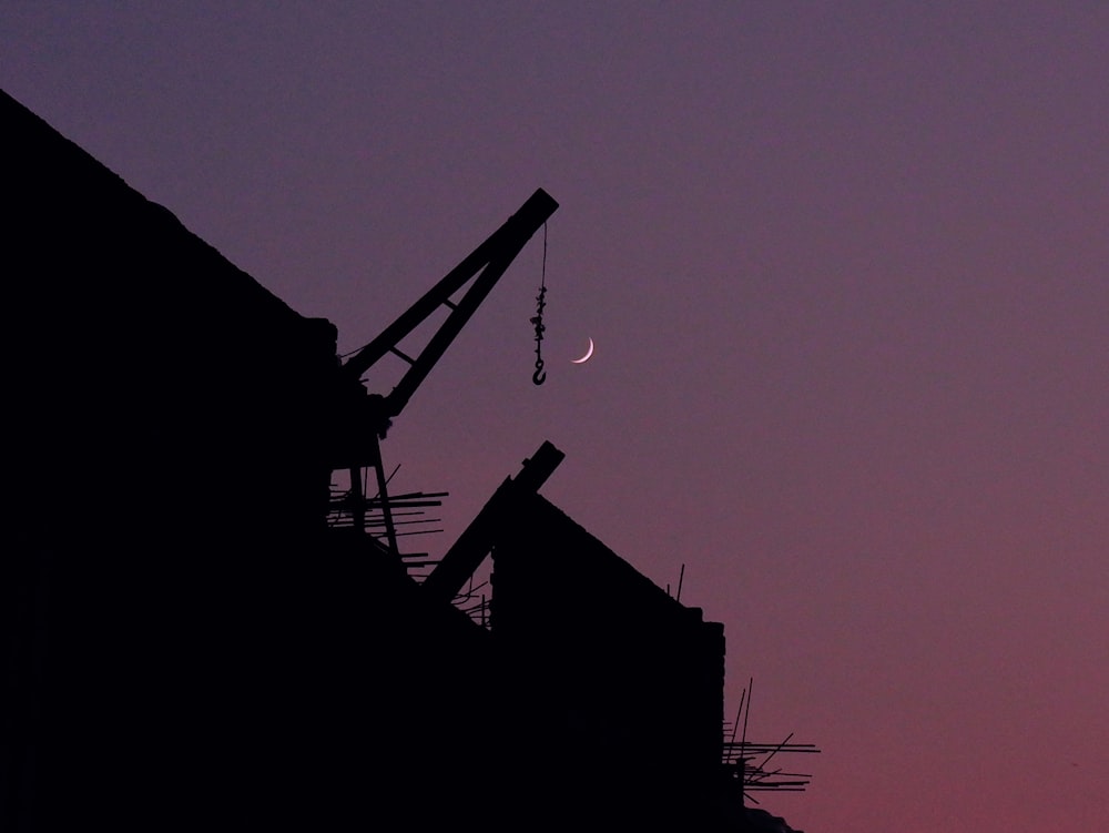 a silhouette of a crane and a moon in the sky