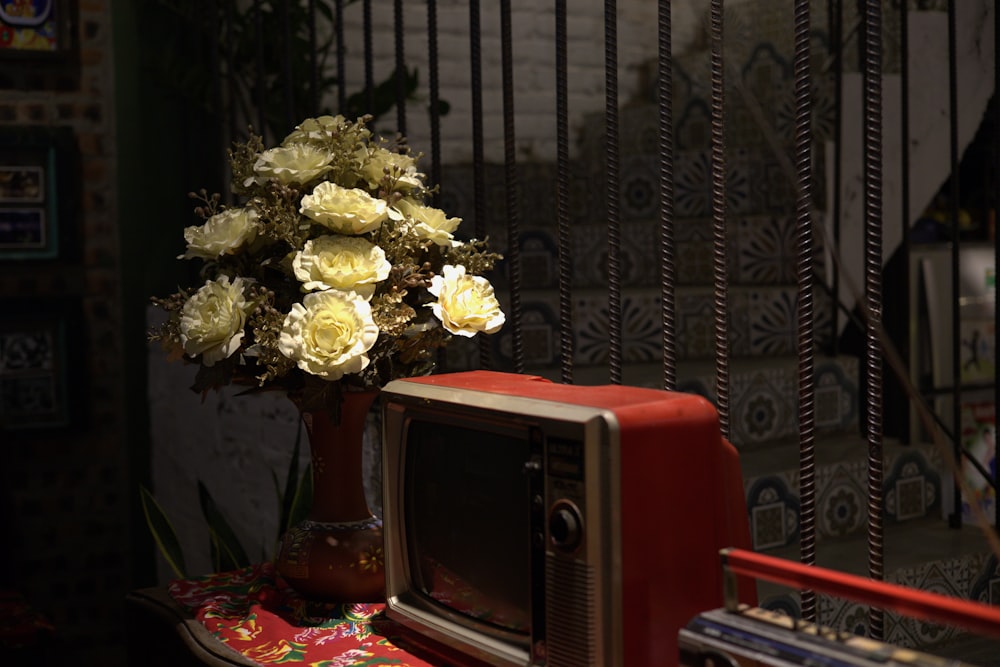 a vase of flowers sits on top of a television