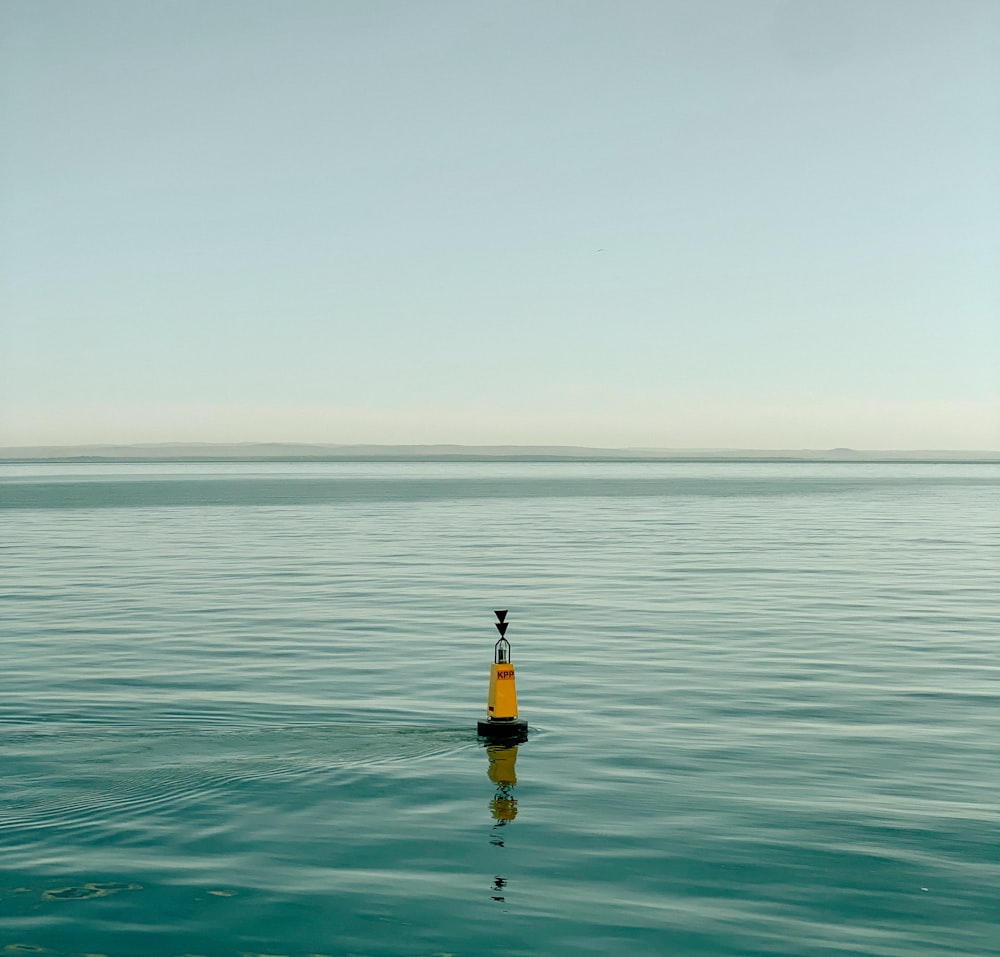 a small yellow buoy in the middle of a body of water
