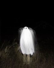 a person standing in a field with a large white object in the back