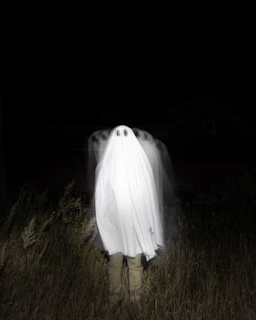 a person standing in a field with a large white object in the back