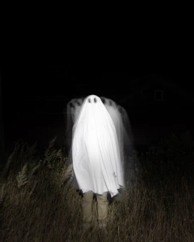 a person standing in a field with a large white object in the back