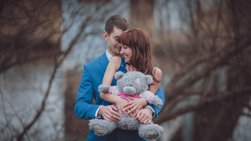 a man and woman holding a teddy bear