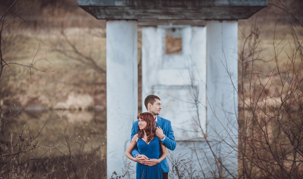 a man and woman hugging in front of a white building