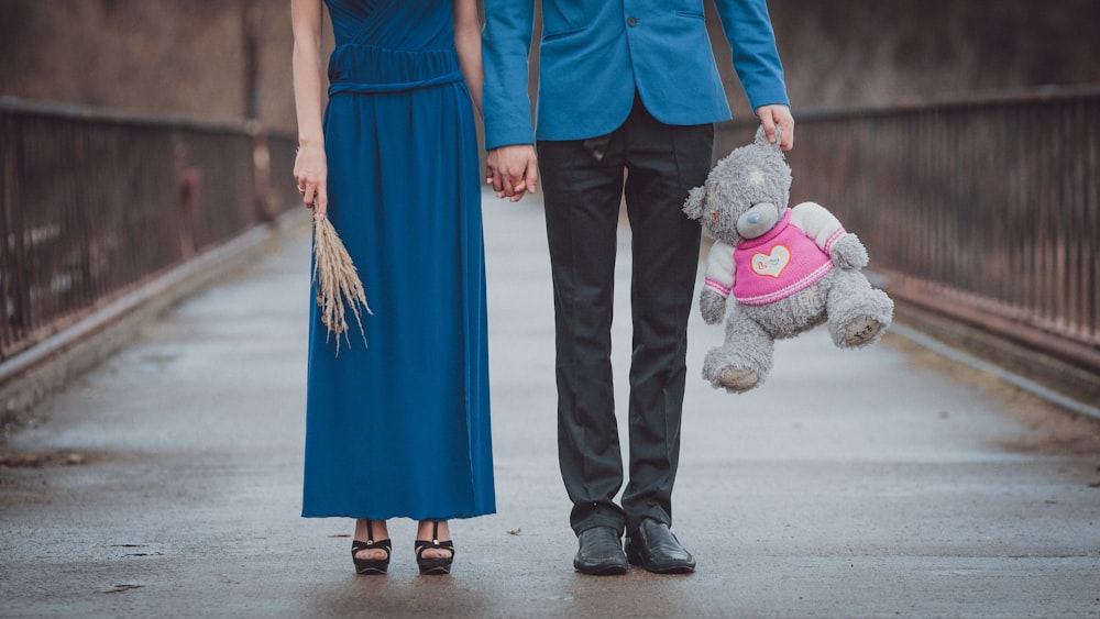 a man and woman holding hands with a stuffed animal