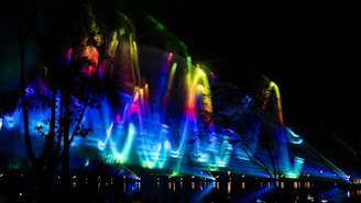 Artistic shot of electric cyan light beams slicing through the night sky above Islamabad.