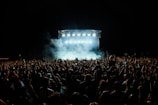 a large crowd of people in front of a stage with lights