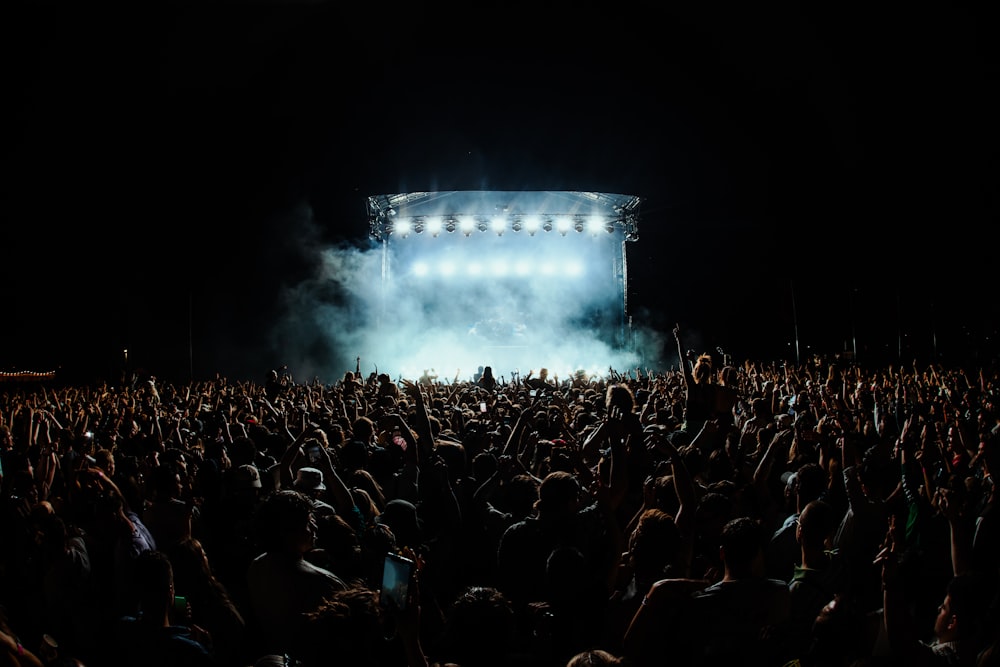 a large crowd of people in front of a stage with lights