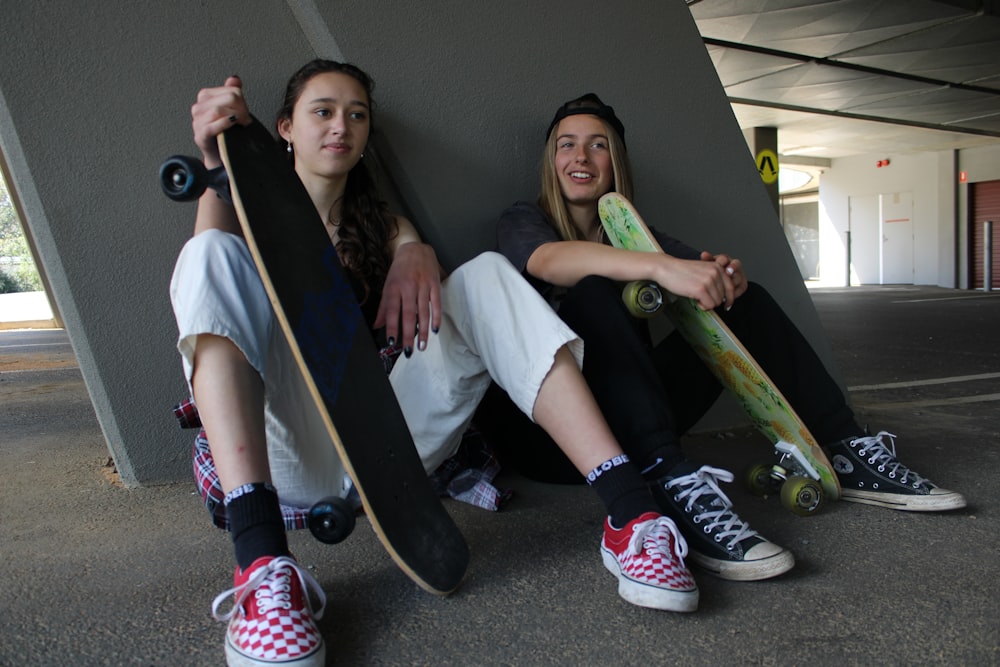 a couple of people sitting on a bench holding skateboards