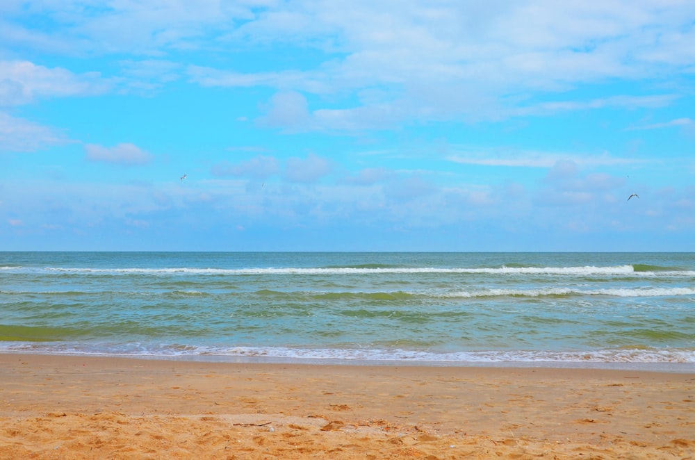 a beach with waves and a blue sky